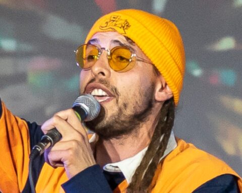 primer plano del rostro del rapero chileno El Chasky, cantando en un concierto con un gorro de lana amarillo