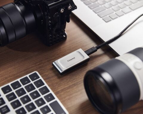 en el centro de la foto un dispositivo de almacenamiento de datos rodeado de un teclado y dos lentes de cámara digital puestos sobre una mesa